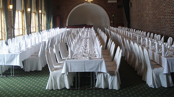 Kolme pitkää illallispöytää katettuna Vanajanlinnan Juhlasalissa.